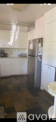 A kitchen with white cabinets and a refrigerator.