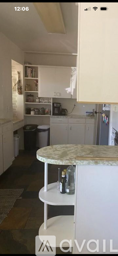 A kitchen with a marble top table and white cabinets.