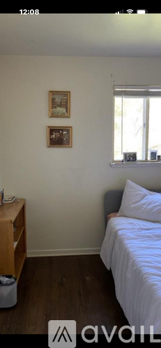 A bedroom with a bed, nightstand, and two pictures on the wall.