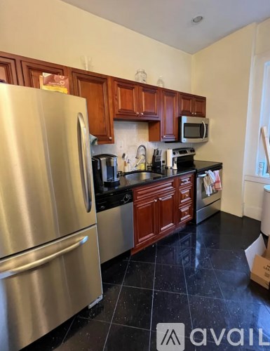 A kitchen with a stainless steel refrigerator and wooden cabinets.