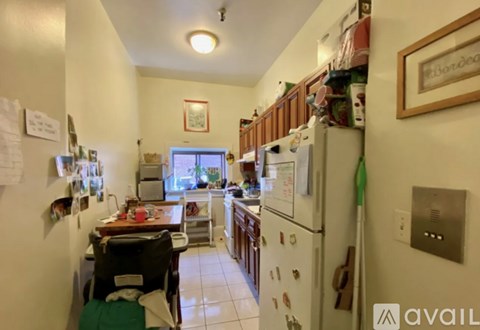 A kitchen with a white fridge and a table with a chair.