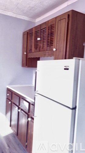 A white refrigerator in a kitchen with wooden cabinets.