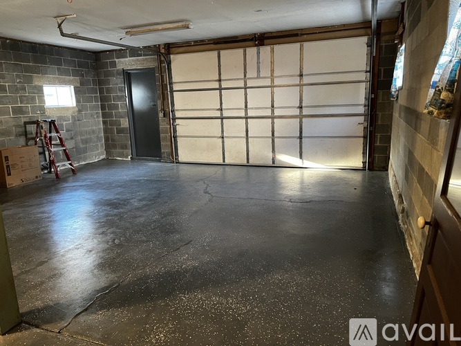 A spacious garage with a concrete floor and a closed white door.