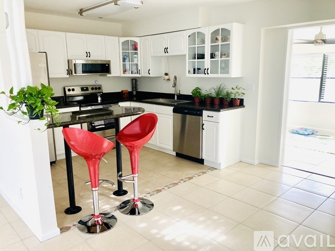 A kitchen with a black countertop and red stools.