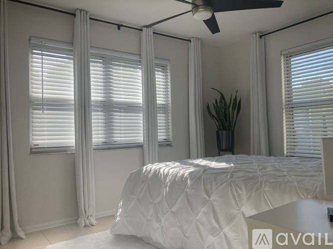 A white bedroom with a large bed and a ceiling fan.