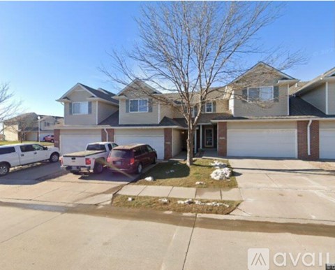 A house with a tree in front and cars parked in the driveway.