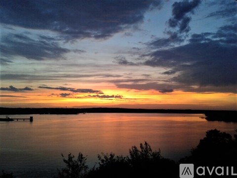 A beautiful sunset over a calm body of water with a dock in the distance.