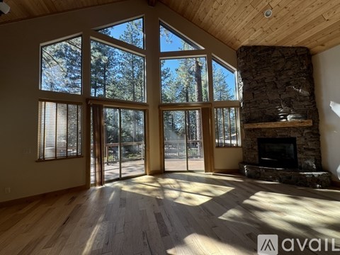 A living room with a stone fireplace and a large window.
