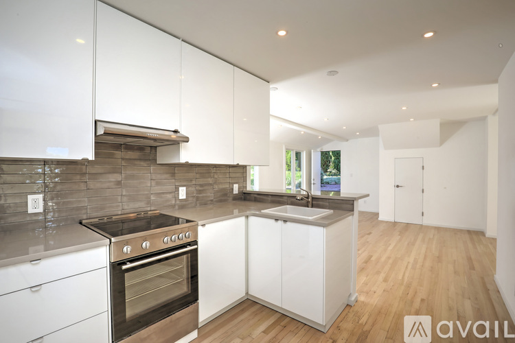 A modern kitchen with white cabinets and a stainless steel oven.