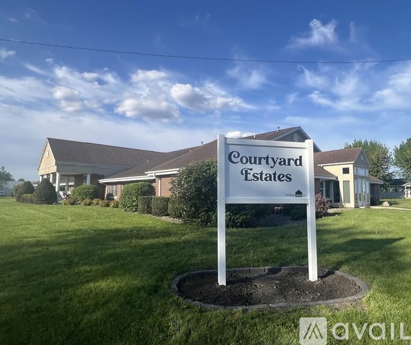 A sign for Courtyard Estates in front of a building.