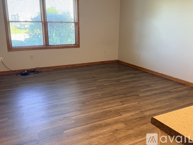 A room with wooden flooring and a window with blinds.