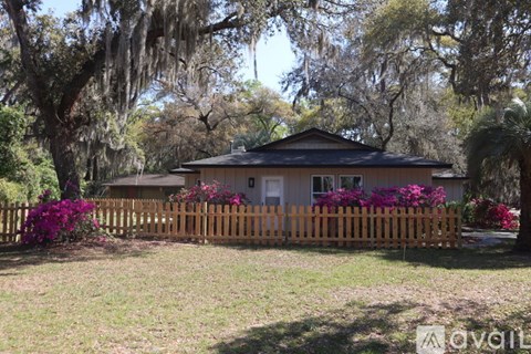 A house with a wooden fence and trees in the background.