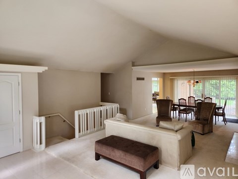 A living room with a white couch and a brown ottoman.