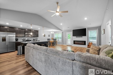 A modern living room with a grey couch and a kitchen in the background.