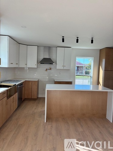 A kitchen with white cabinets and wooden floors.