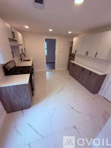 A kitchen with white cabinets and a marble floor.