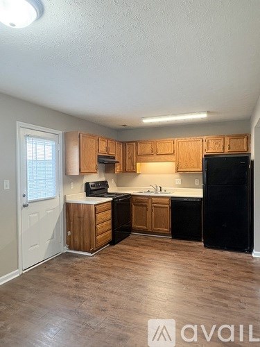 A kitchen with wooden cabinets and a black refrigerator.