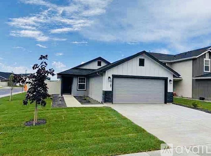 A house with a grey garage door and a tree in front.
