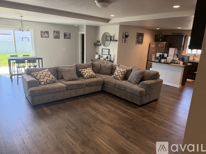 A living room with a large sectional sofa and a kitchen area in the background.