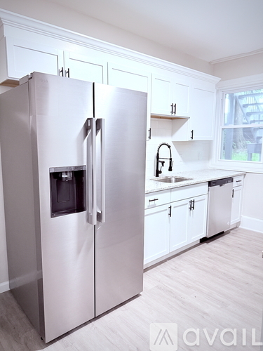 A modern kitchen with a stainless steel refrigerator and white cabinets.
