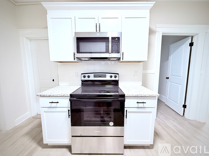 A kitchen with white cabinets and a black stove top oven.