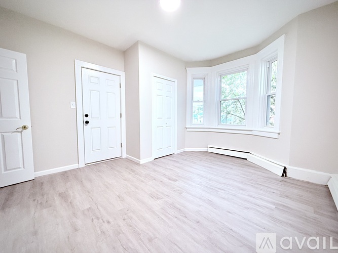A room with white doors and a window with a view of trees.