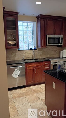 A kitchen with brown cabinets and a black counter top.
