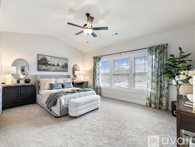 A bedroom with a large bed, a ceiling fan, and a painting on the wall.