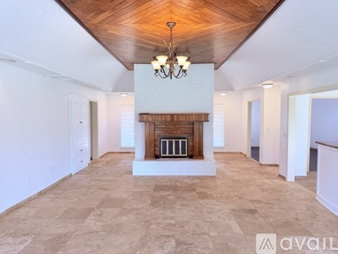 A large, empty room with a fireplace and a chandelier.