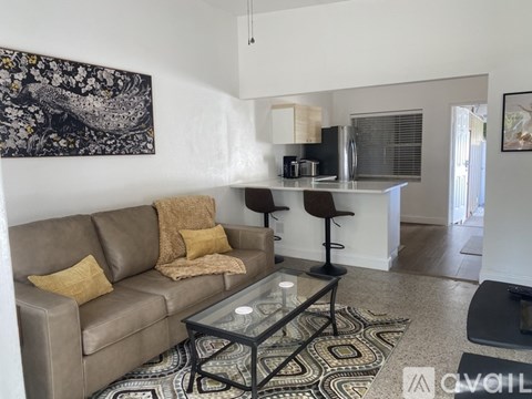 A living room with a brown couch and a glass coffee table.