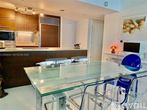 A modern kitchen with a glass table and blue chair.
