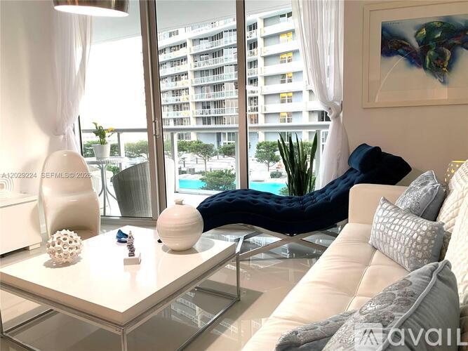 A modern living room with a large window overlooking a pool and a building.