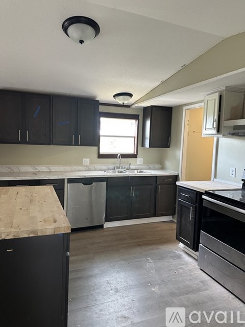 A kitchen with black cabinets and a wooden island.