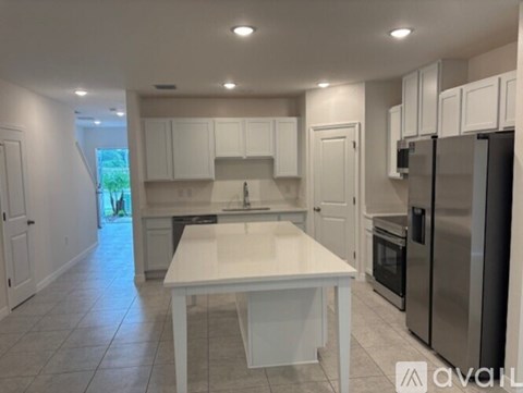 A kitchen with white cabinets and a white island.