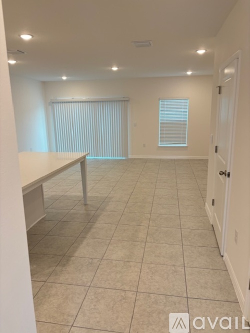 A spacious room with tiled flooring and a table set up in the corner.