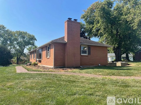 A brick house with a chimney and a grassy lawn in front.