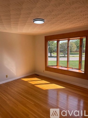 A room with wooden floors and a window showing a lawn outside.