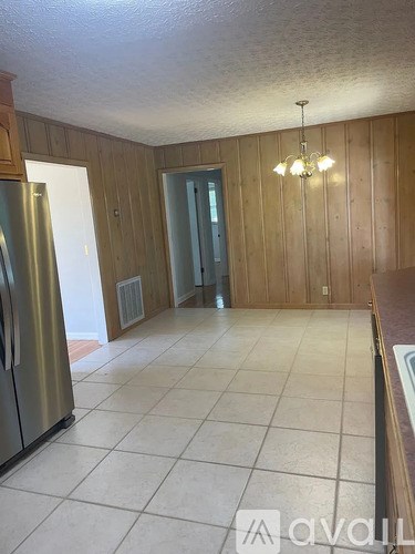 A kitchen with a refrigerator and a chandelier.