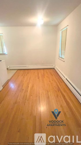A room with wooden flooring and a Vodock Apartments logo.