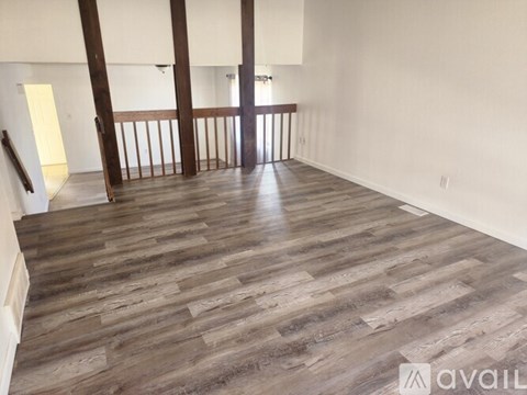 A spacious room with wooden flooring and white walls.