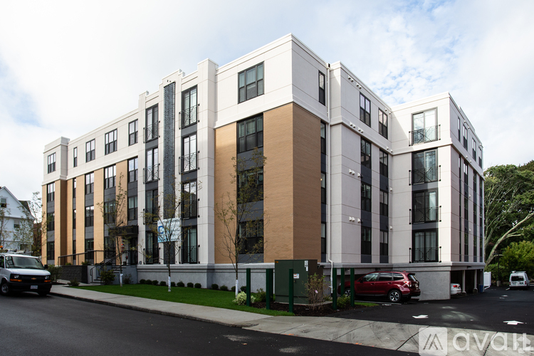 A modern multi-story apartment building with cars parked in front.