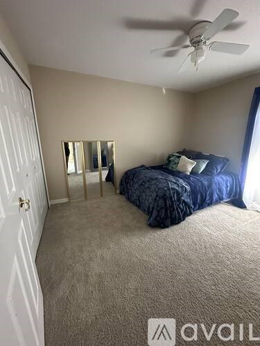 A bedroom with a bed, dresser, mirror, and a ceiling fan.