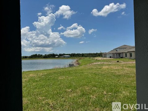 A house is situated by a body of water with a grassy area in front.
