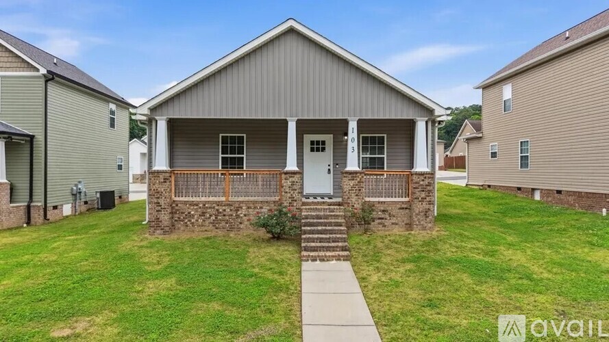 A house with a front porch and a stone wall is for sale.