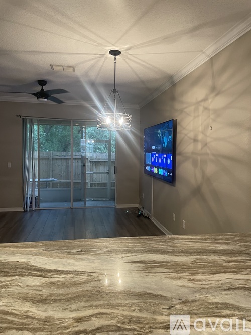 A living room with a flat screen TV mounted on the wall and a ceiling fan.