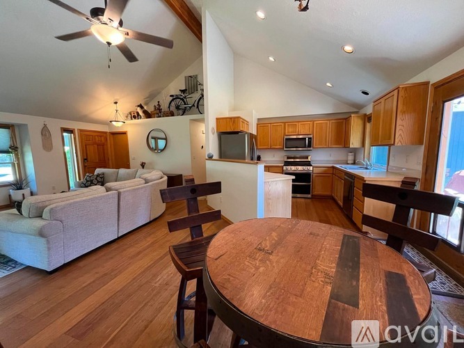 A living room with a couch, a dining table, and a kitchen area in the background.