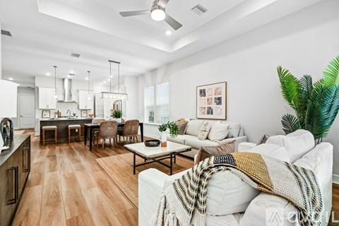 A living room with a white couch and a wooden floor.