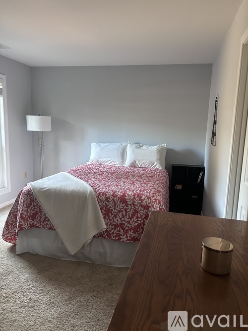 A bedroom with a bed covered in a red and white patterned bedspread.