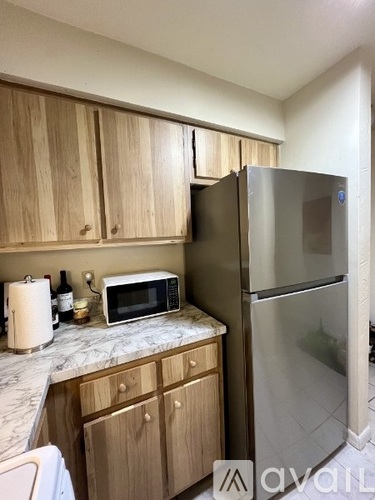 A kitchen with wooden cabinets and a stainless steel refrigerator.