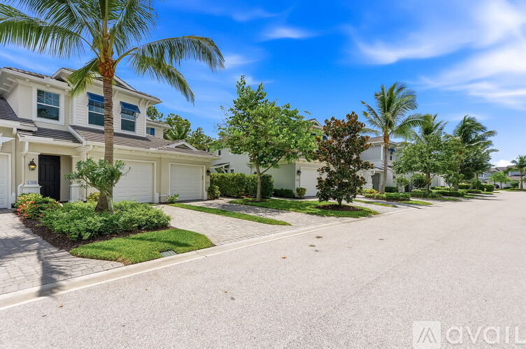 A residential street with houses on both sides and palm trees in the background.